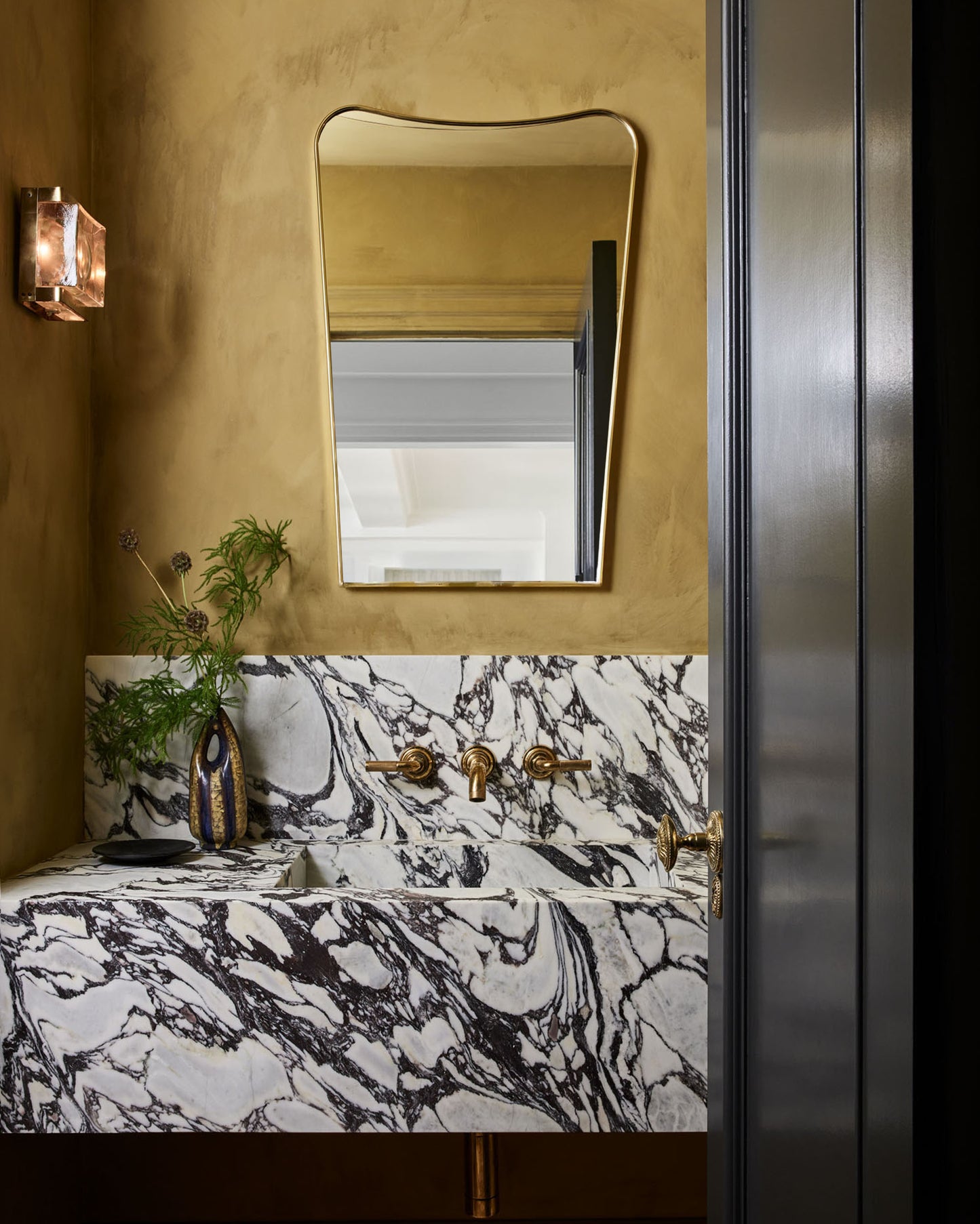 curved brass mirror in bathroom