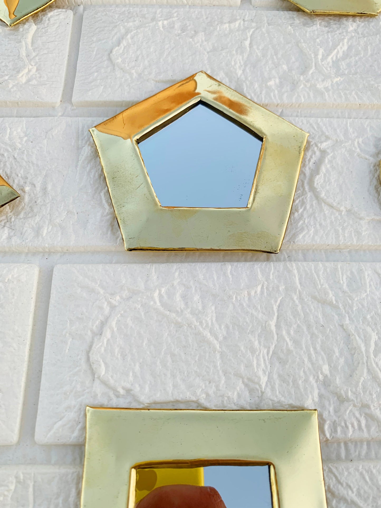 a hand holding a mirror in front of a white tiled wall