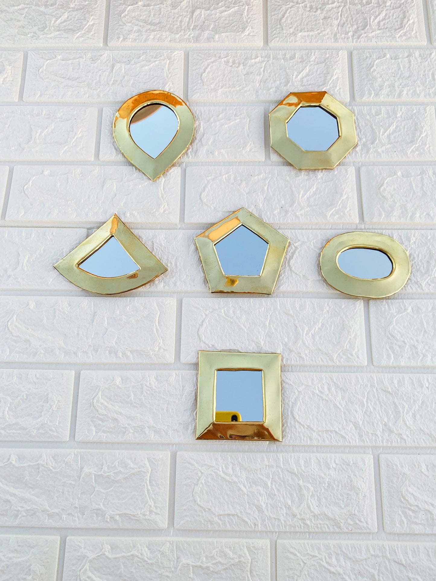 a white tiled wall with four mirrors on it