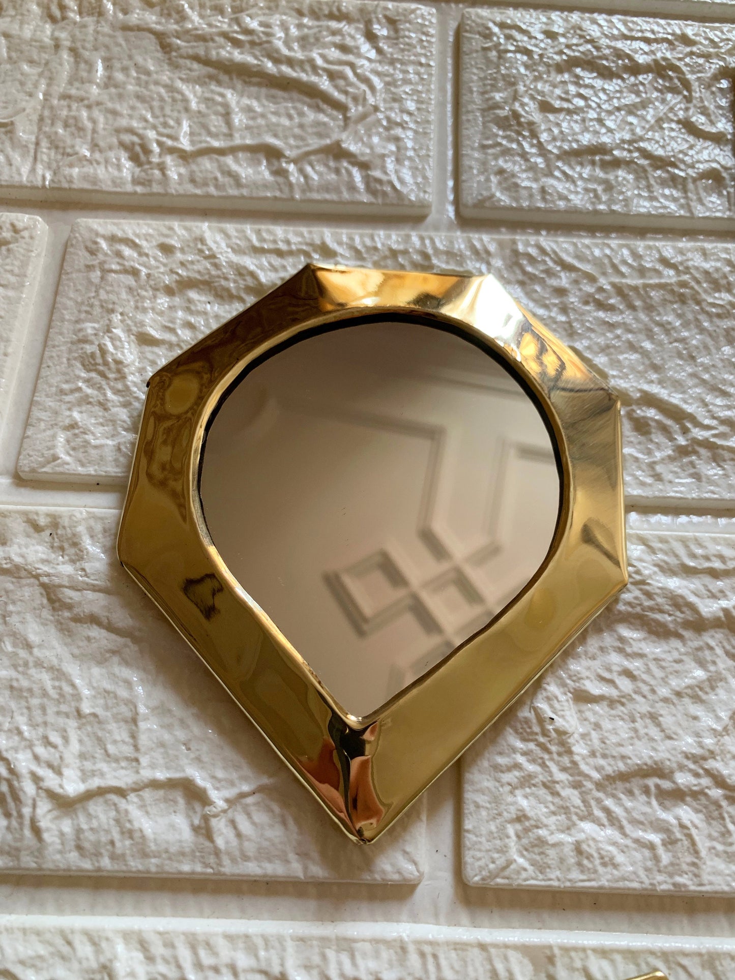 a mirror mounted to the side of a white brick wall