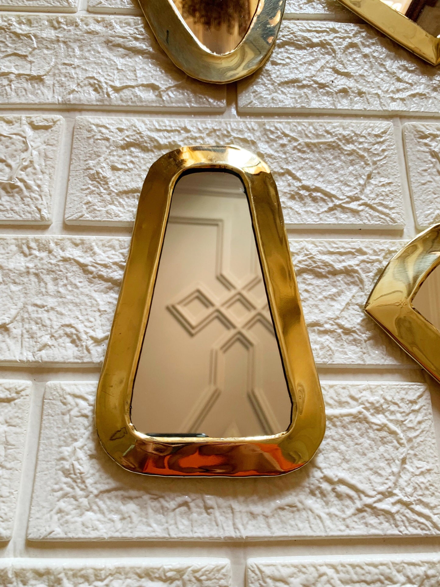 a white brick wall with a mirror and a gold frame