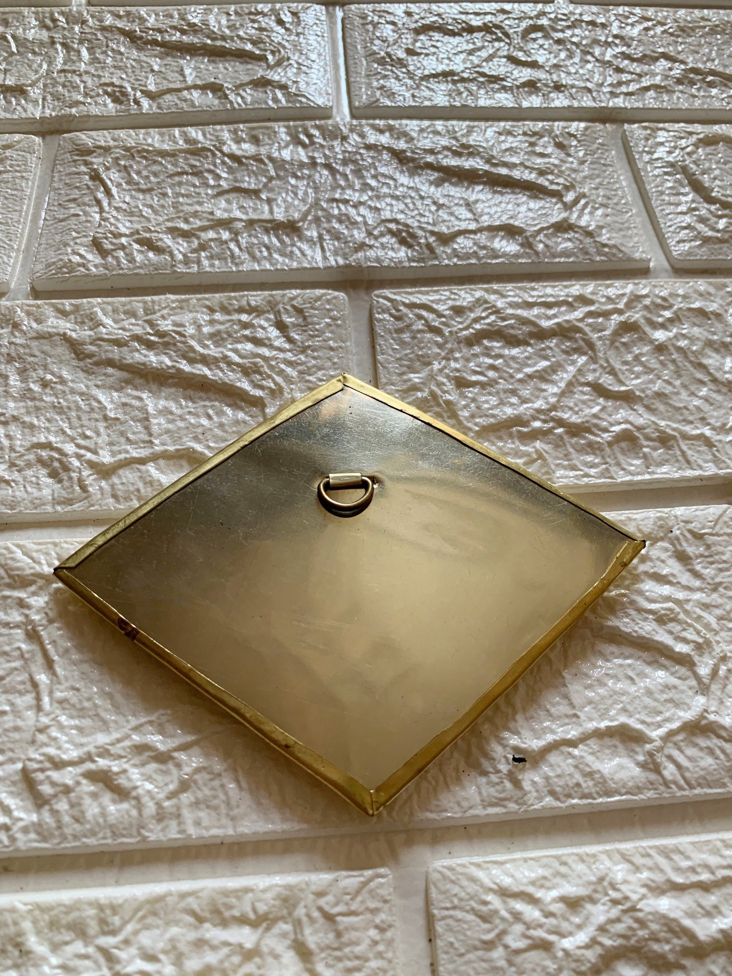 a square metal object mounted to a brick wall