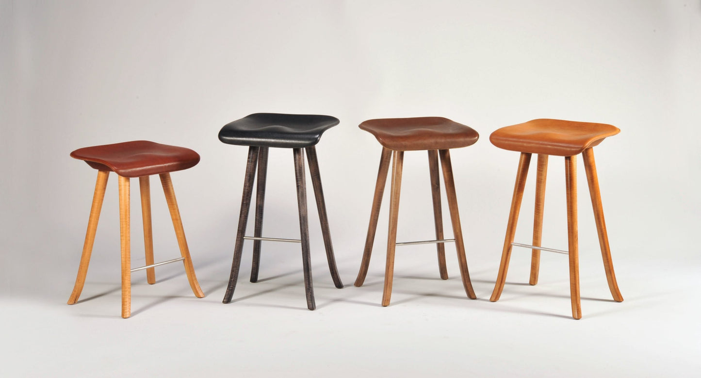 Four stools with different wood finishes on a white background