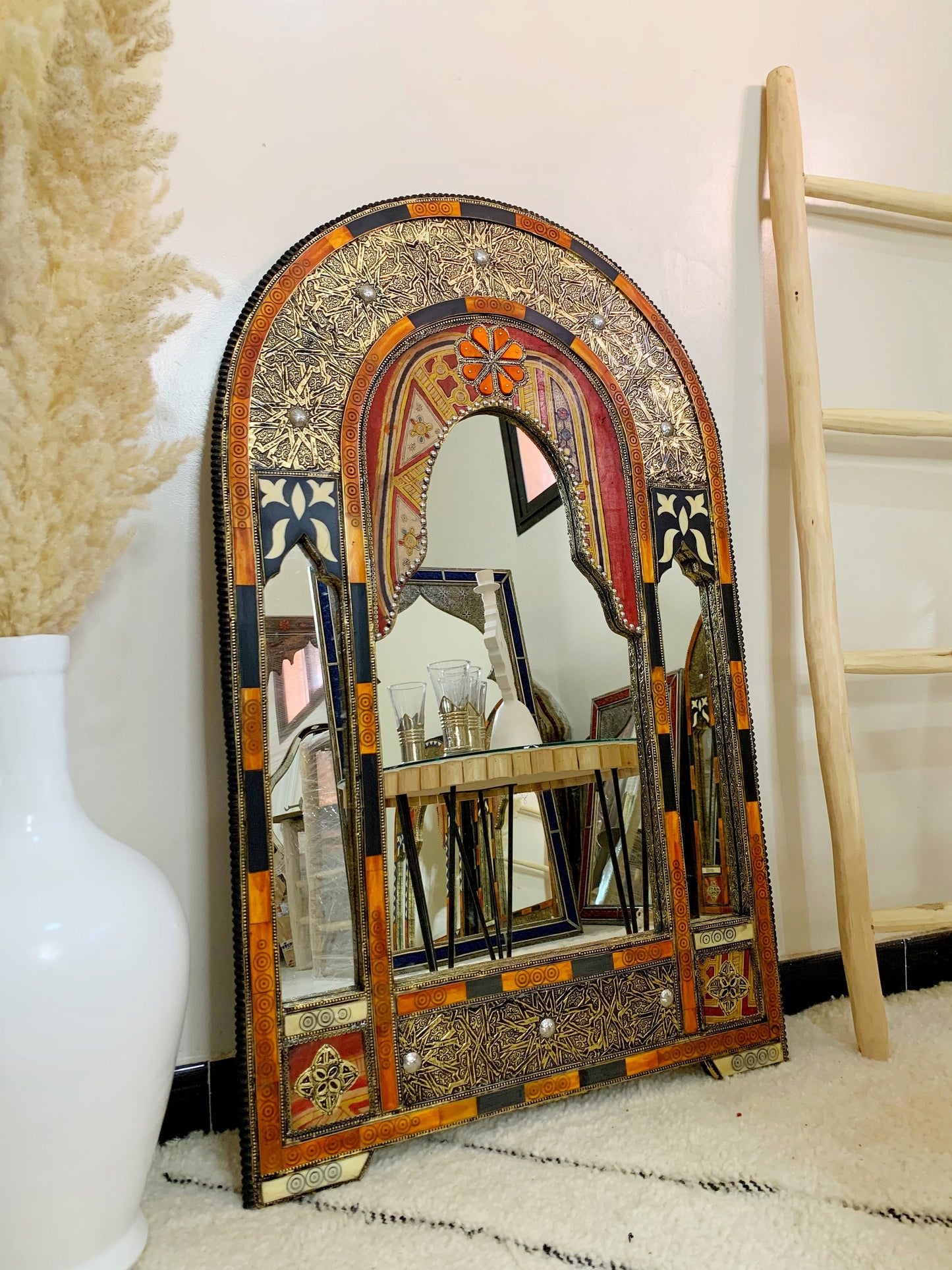 a mirror sitting on the floor next to a vase