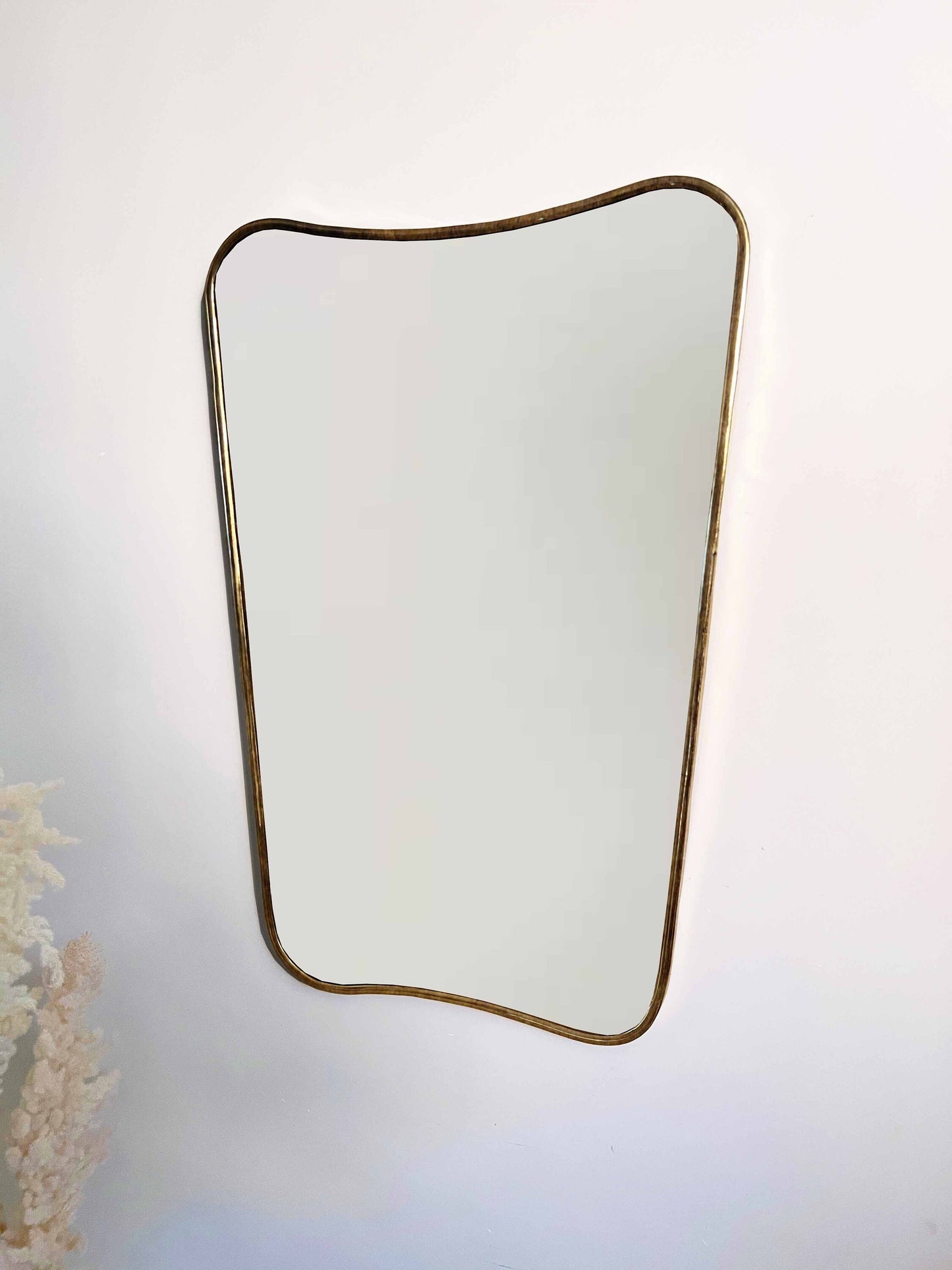 a Butterfly Mirror hanging on a wall next to a vase