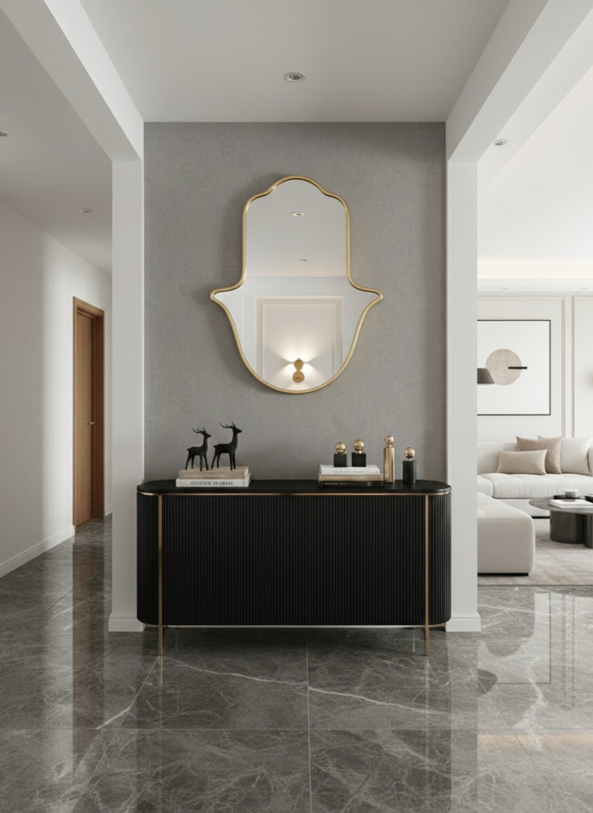 Gold Hamsa wall mirror above black console in modern entryway.