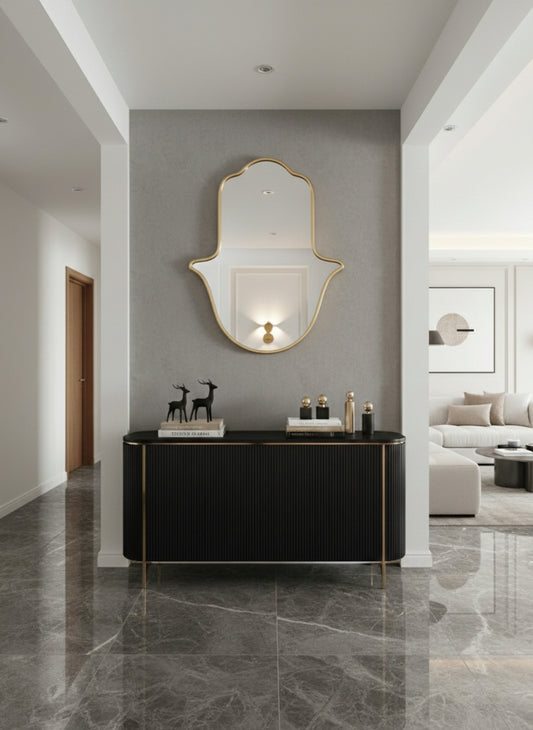 Gold Hamsa wall mirror above black console in modern entryway.