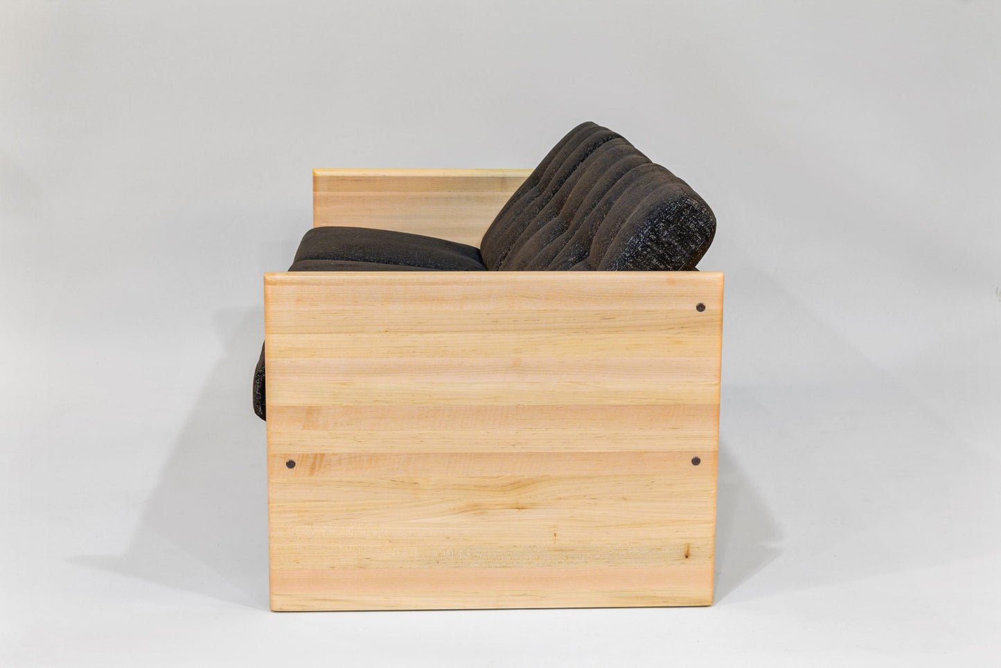 Wooden storage bench with black cushions on a gray background