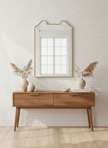 Double arch crest brass mirror above wooden console table