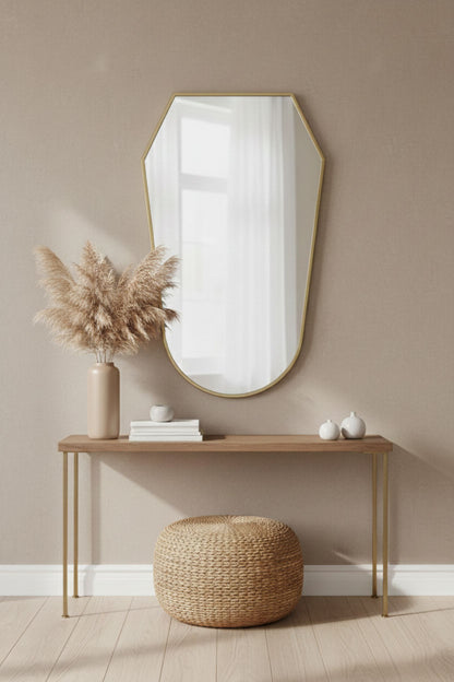 Rounded shield brass mirror above console table in neutral entryway