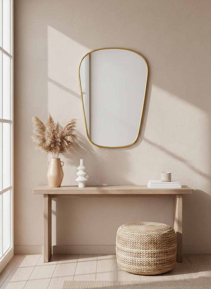  brass wall mirror above console table in minimalist entryway