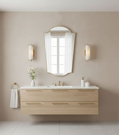 Rounded crest brass mirror above modern floating vanity in neutral bathroom