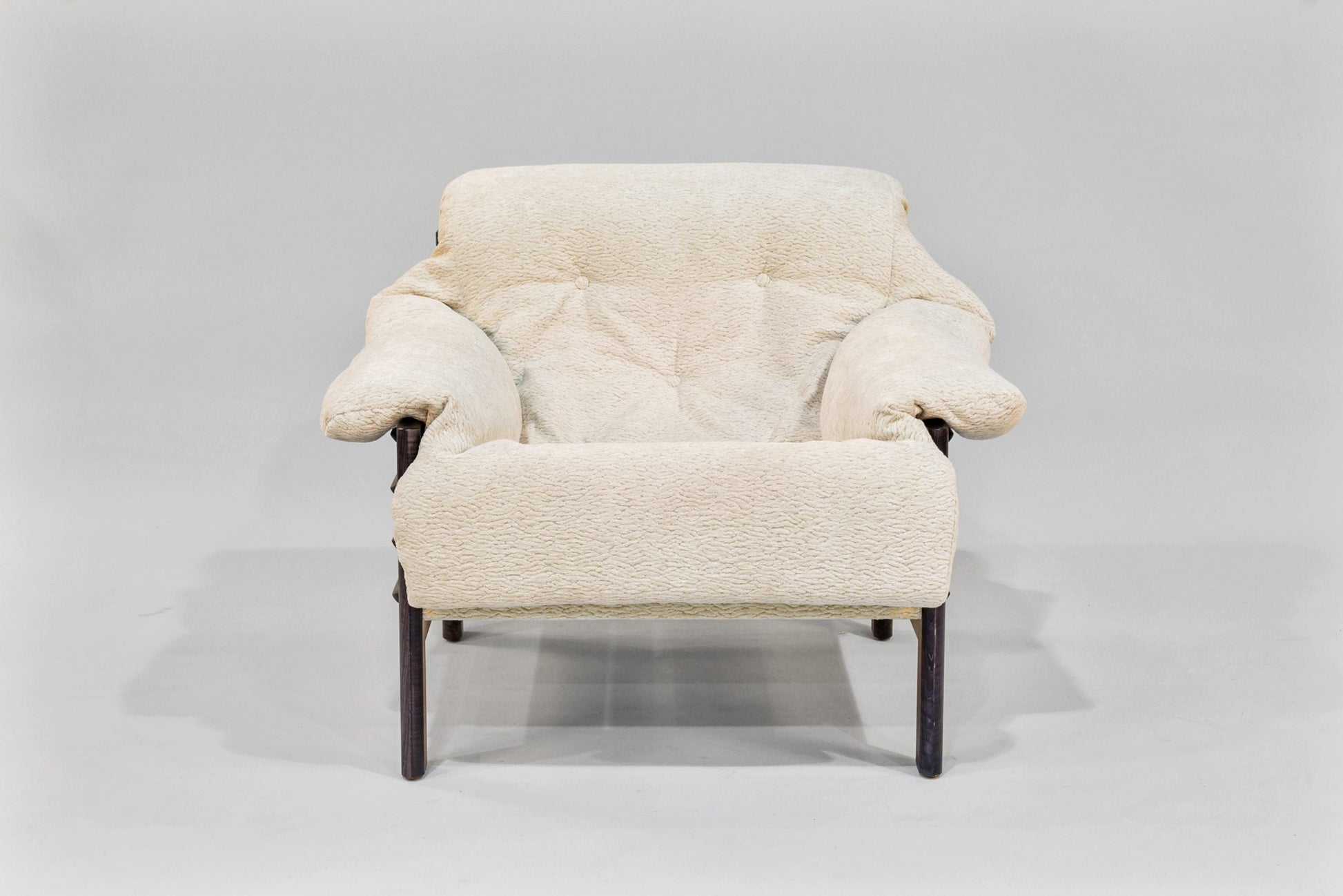 Cream-colored armchair with wooden legs on a light gray background
