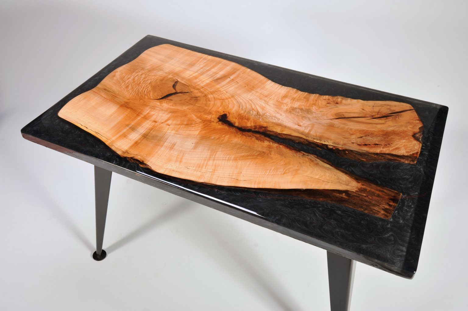 Wooden table with black resin finish on a white background