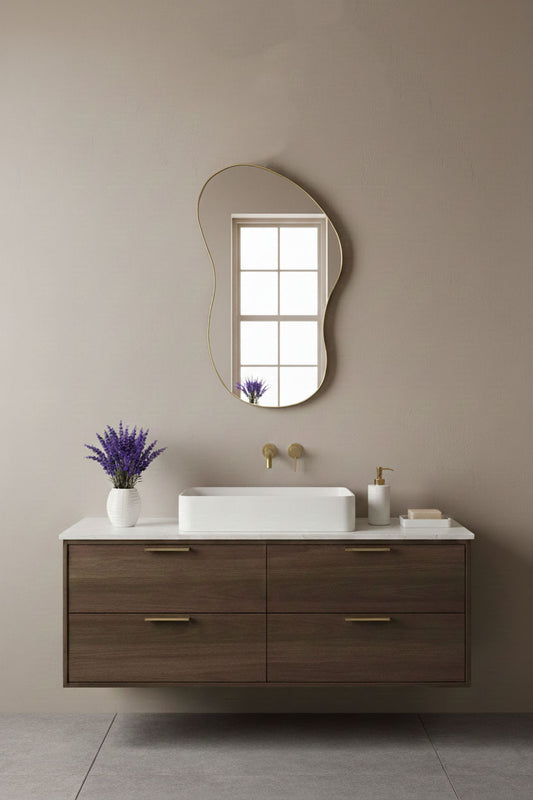 Artisan freeform mirror with brass frame above modern bathroom vanity