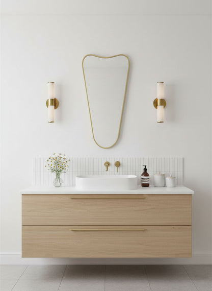 Soft Cone brass vanity mirror mounted above a floating bathroom sink