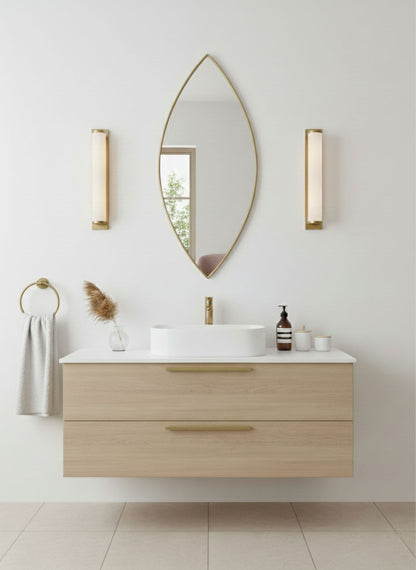 Leaf-shaped brass mirror above a modern floating vanity