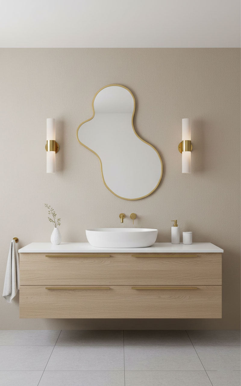 Amoeba-shaped brass mirror over a minimalist bathroom vanity