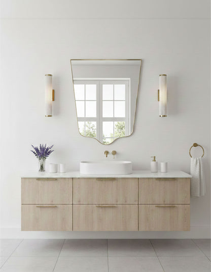 Crest-edge brass vanity mirror styled above a modern floating bathroom sink