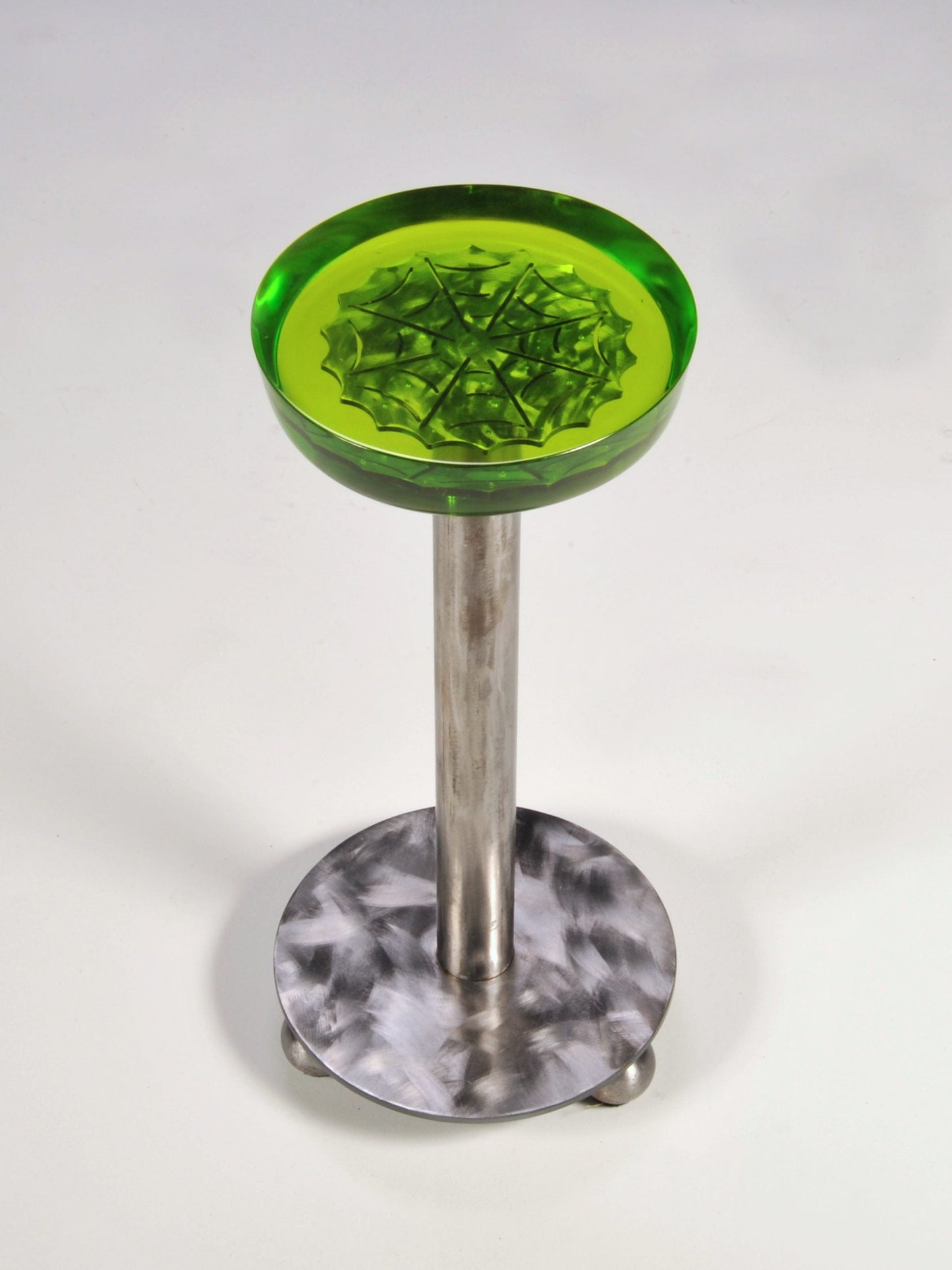 Green glass stool with a metallic base on a white background