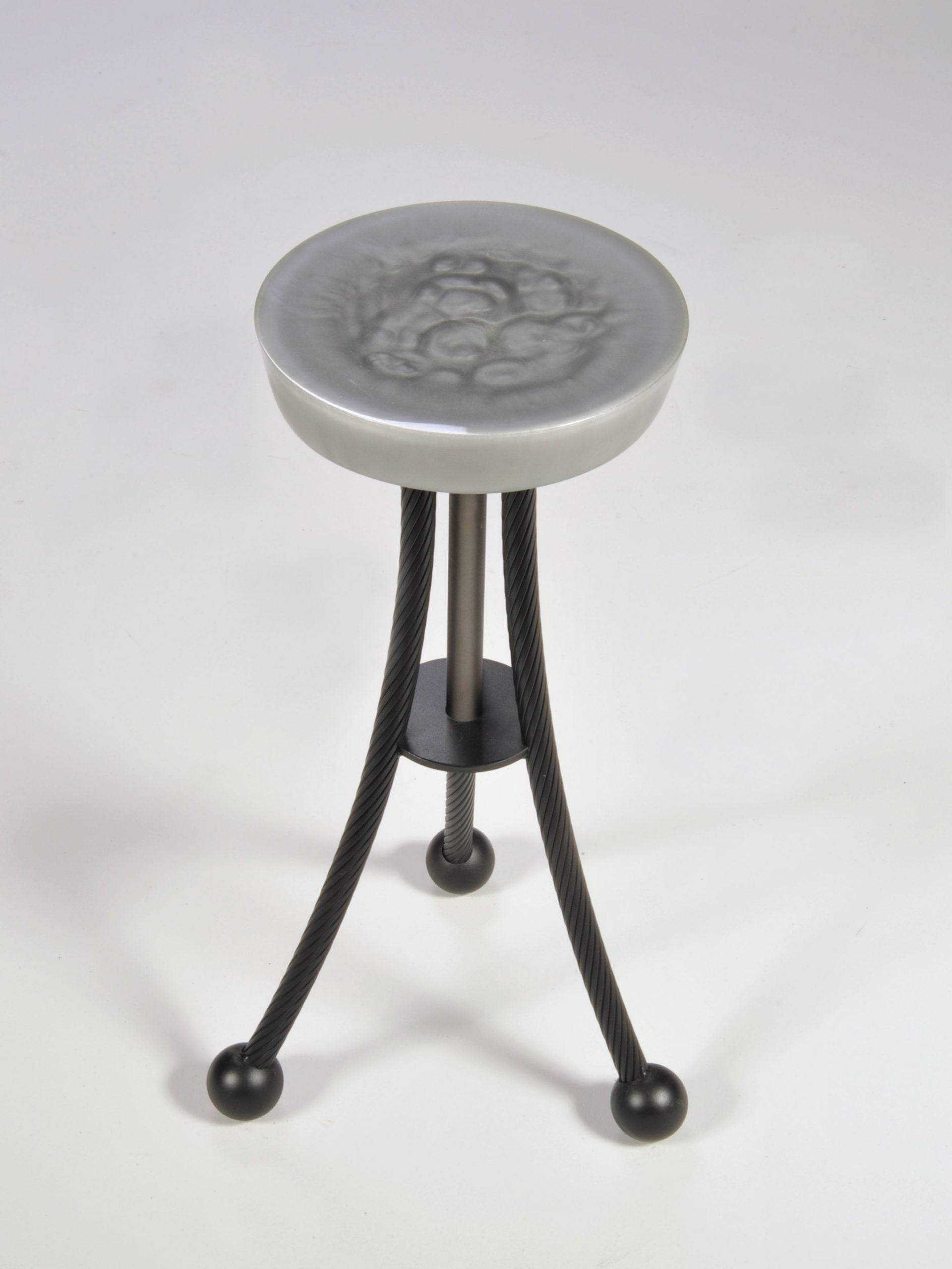 Stool with decorative top and black metal legs on a white background