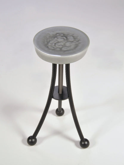 Stool with decorative top and black metal legs on a white background