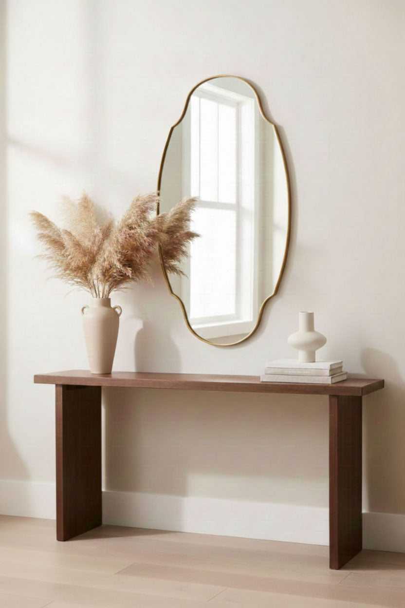 Decorative oval brass mirror above wooden console table