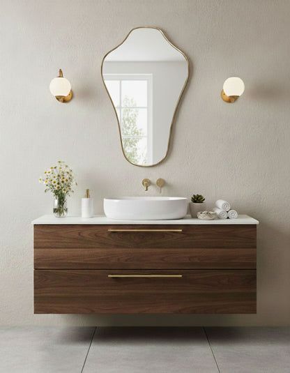Sculpted crest brass vanity mirror in minimalist bathroom with warm lighting