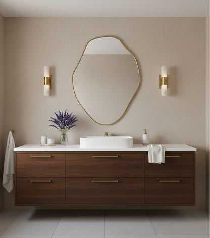 Organic freeform brass mirror styled above wooden vanity in modern bathroom