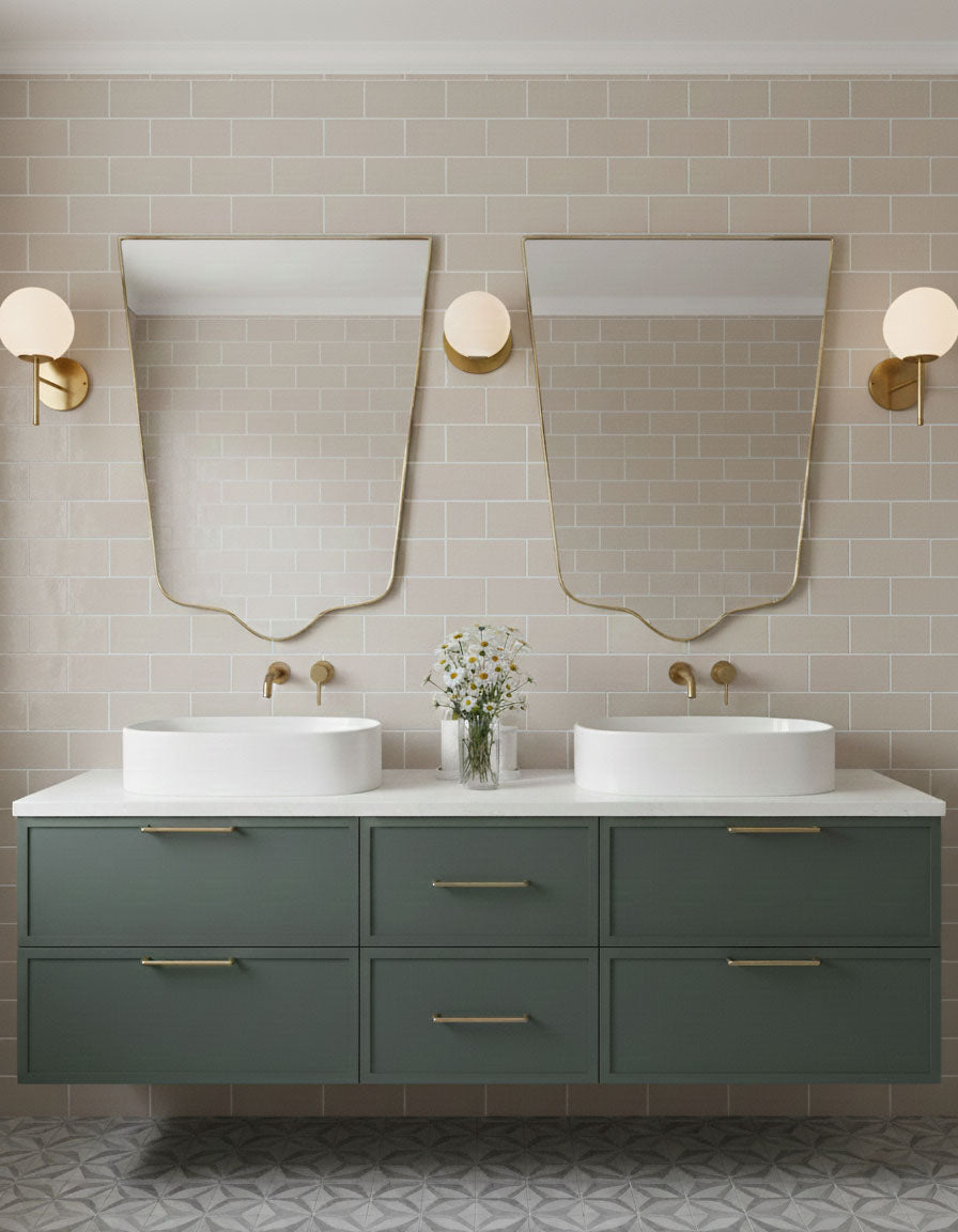 Pair of crest-edge brass mirrors over double bathroom vanity with green cabinetry