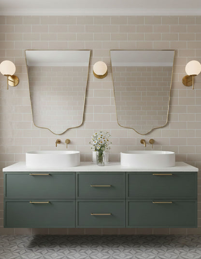 Pair of crest-edge brass mirrors over double bathroom vanity with green cabinetry