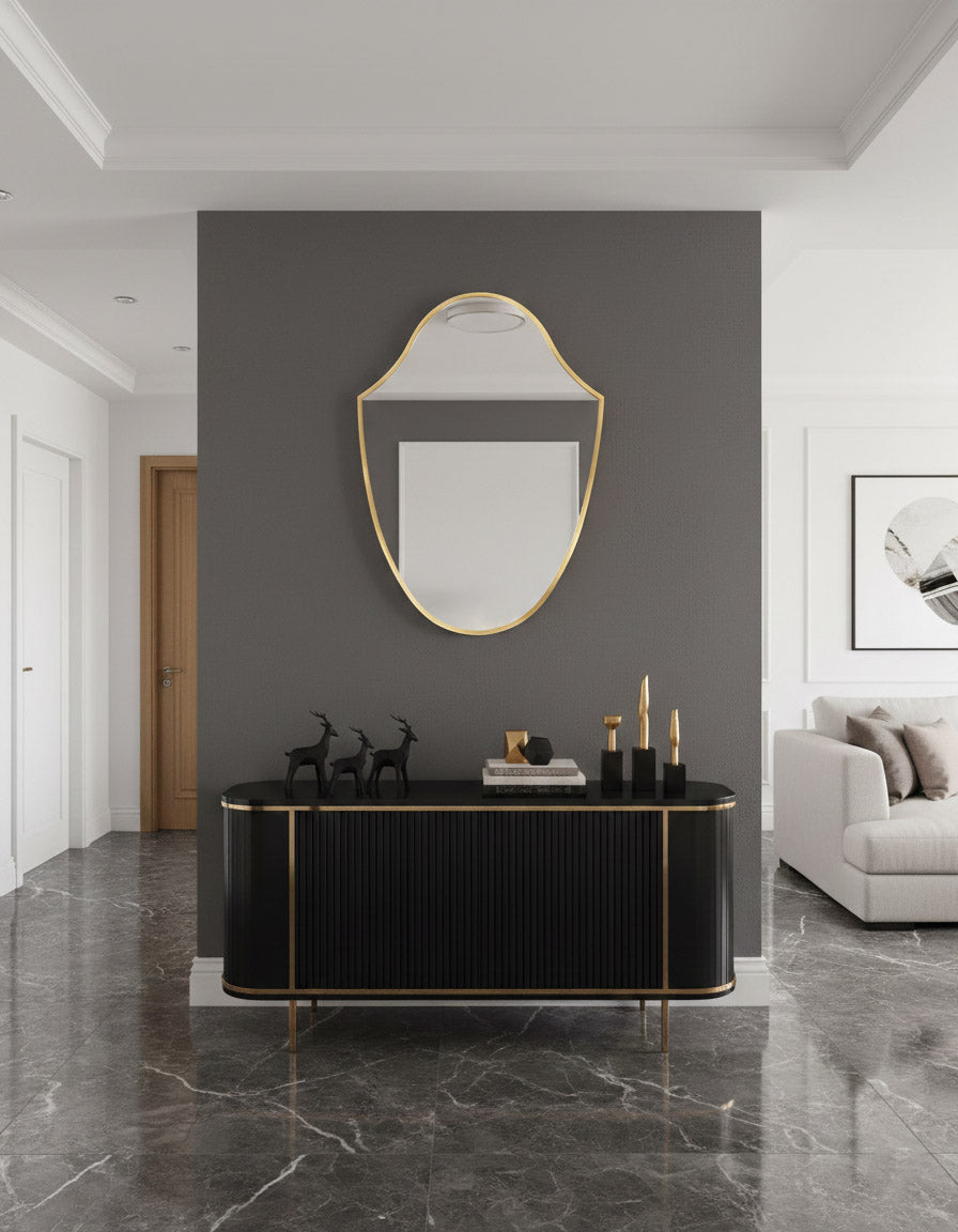 Modern interior with a black console table, gold-framed mirror, and gray sofa.