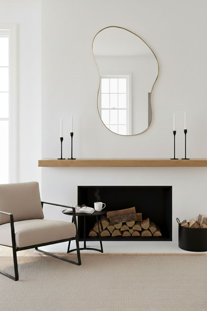 Handmade freeform brass mirror displayed above fireplace mantel