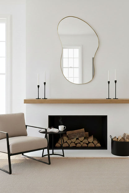 Handmade freeform brass mirror displayed above fireplace mantel