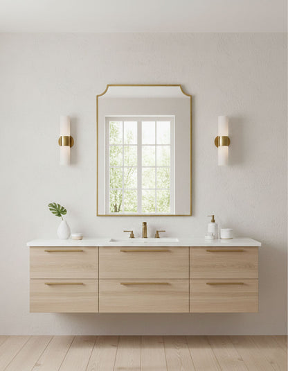 Modern brass chateau mirror mounted above floating bathroom vanity