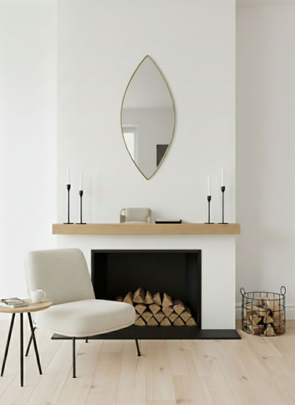 Leaf silhouette brass mirror above a minimalist fireplace