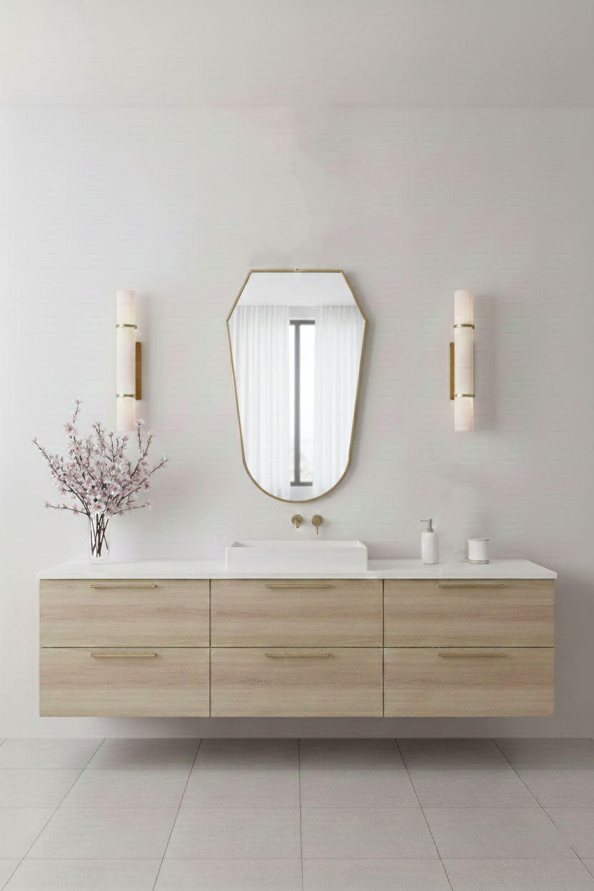 Rounded shield mirror with brass frame styled above floating wood vanity