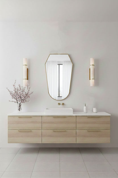 Rounded shield mirror with brass frame styled above floating wood vanity