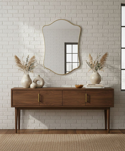 Wavy shield brass mirror above wooden console