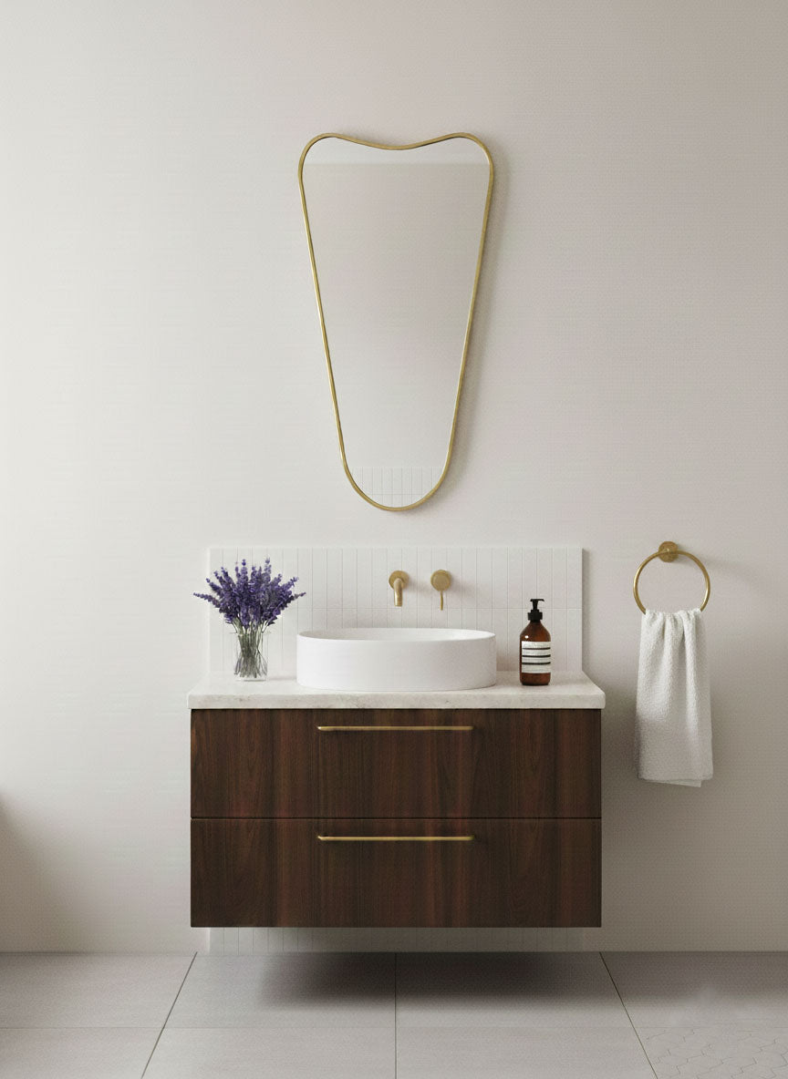 Soft Cone brass mirror above dark wood floating vanity in modern bathroom