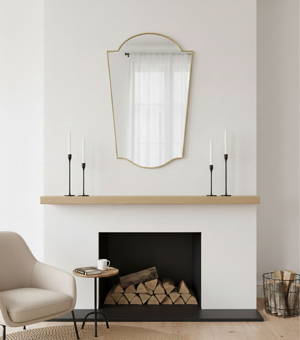 Rounded crest brass mirror mounted above fireplace mantel