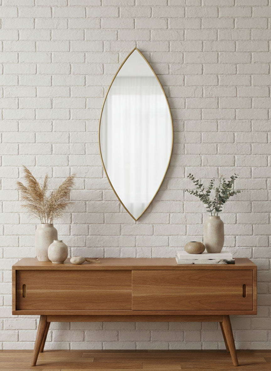 Leaf-shaped brass mirror above a wooden console table