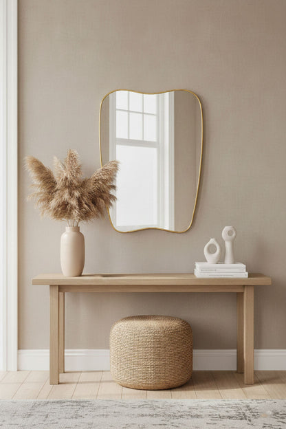 Modern soft-crest mirror with brass frame in neutral entryway