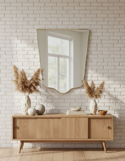 Crest-edge brass wall mirror styled above wooden console in living space