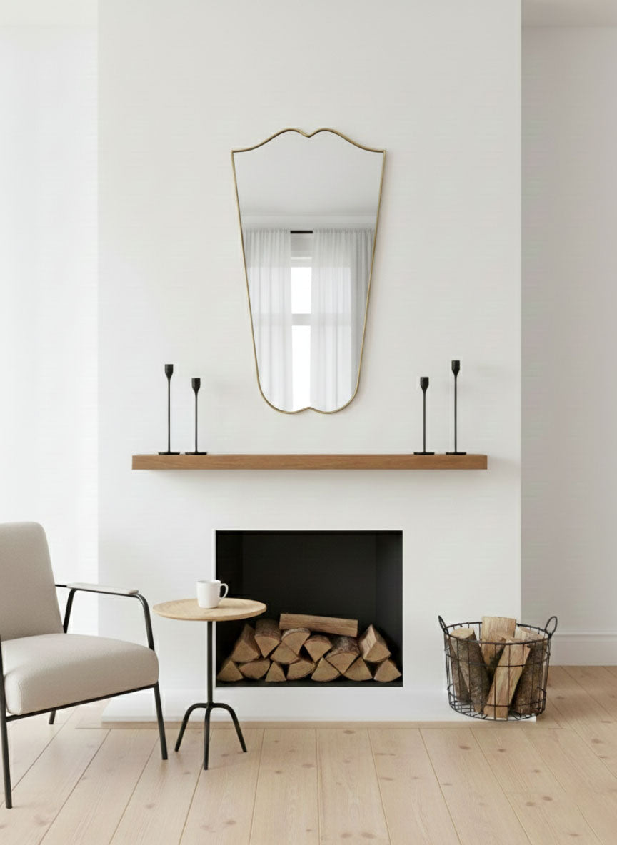 Gentle Wave Crest brass mirror displayed above fireplace mantel