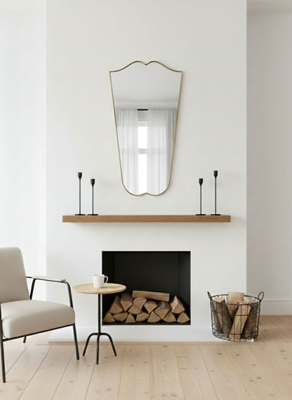 Gentle Wave Crest brass mirror displayed above fireplace mantel