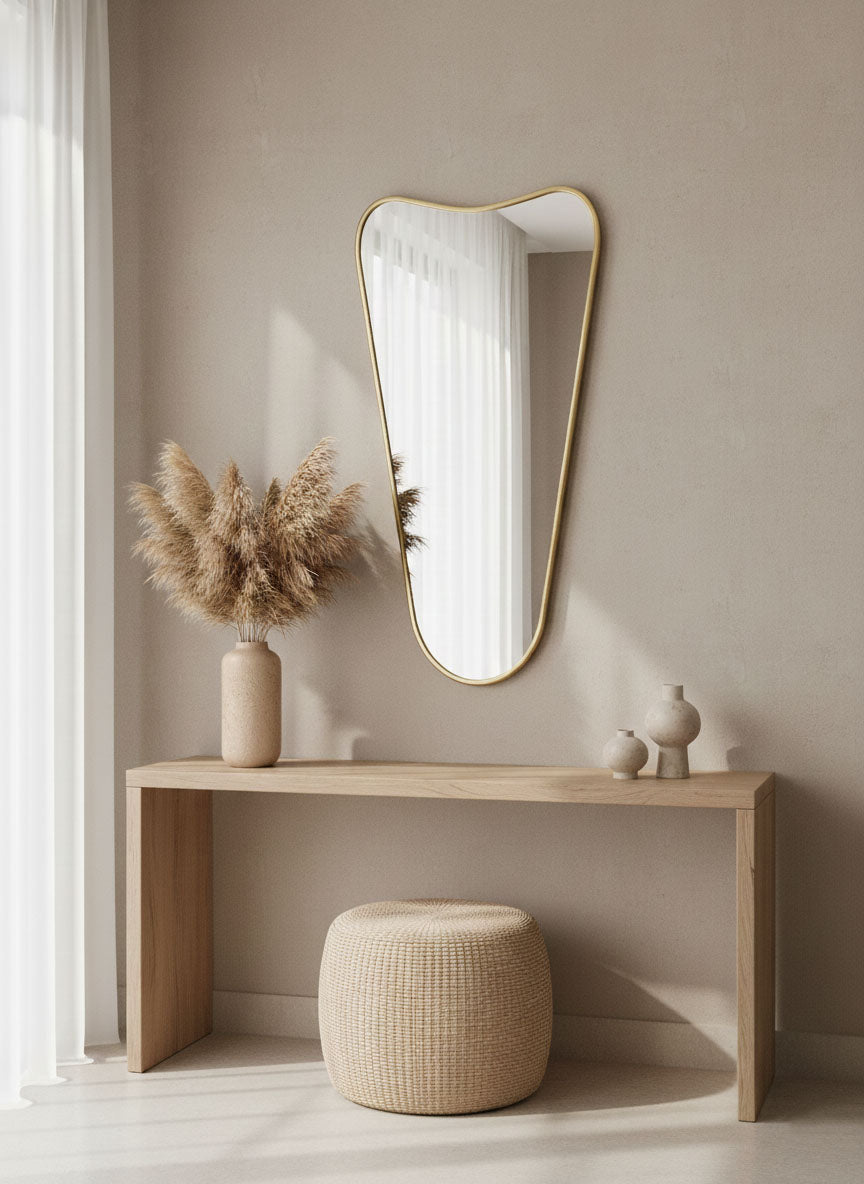 Soft Cone brass wall mirror styled in minimalist entryway with console table