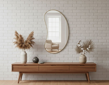 Organic bean-shaped brass mirror styled on brick wall console