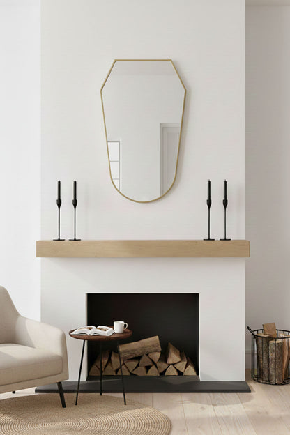 Rounded shield mirror with brass frame mounted above fireplace mantel