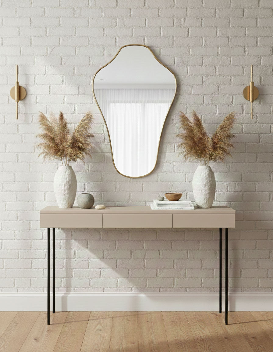 Sculpted crest brass mirror displayed above console table with neutral decor